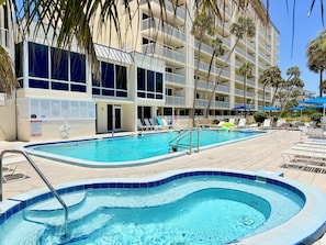 A hotel pool area with a hot tub, lounge chairs, and a sign indicating no diving.