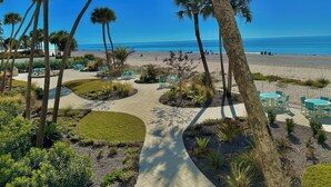 A landscaped area with palm trees, a paved walkway, and outdoor seating.