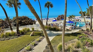 A resort with a pool area, palm trees, and a view of the beach.