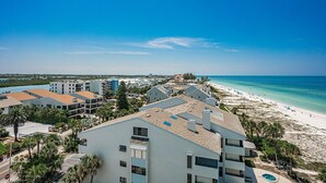 A coastal hotel with multiple buildings, a beach, and a clear blue sky.