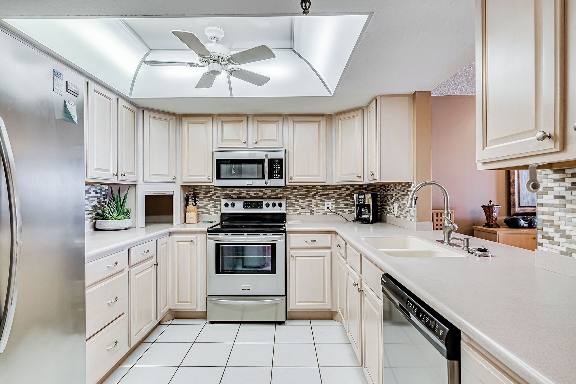 A modern kitchen with white cabinets, a built-in oven, a microwave, and a dishwasher.
