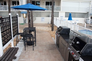 An outdoor patio area with a grill, a table with chairs, and a blue umbrella. - Sand Castle II 2503 - GULF FRONT Condo! (Indian Shores)