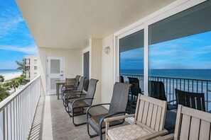 A balcony with outdoor furniture, a door, and a view of the beach.