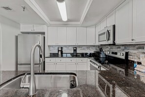 A modern kitchen with white cabinets, stainless steel appliances, and a granite countertop.