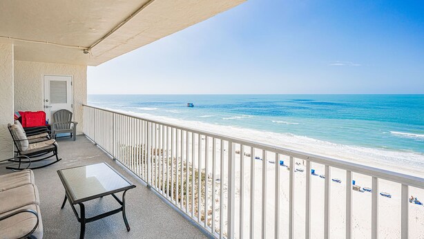 Ein Balkon mit Blick auf den Strand, eine Tür und eine Sitzgelegenheit mit Tisch.