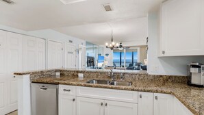 A modern kitchen with white cabinetry, granite countertops, and a built-in dishwasher.