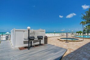 Ein Poolbereich mit Grillstation, Liegestühlen und Meerblick.