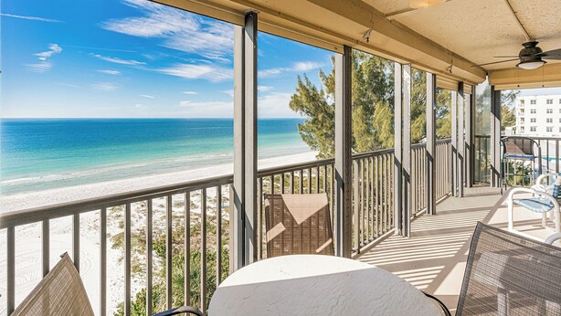 A covered balcony with a view of the beach and ocean.
