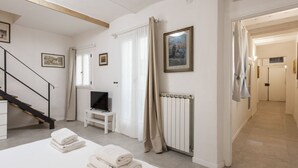 A hotel room with a bed, a TV, a radiator, a staircase, and a hallway. - Santa Croce View 1 by Mmega (Firenze)