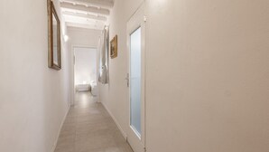 A narrow hallway with white walls, a door with frosted glass, and a light fixture on the ceiling. - Santa Croce View 1 by Mmega (Firenze)
