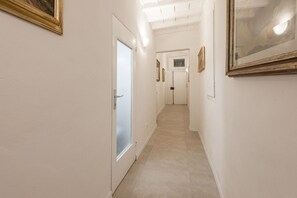 Un couloir avec une porte, des tableaux encadrés et un sol carrelé.