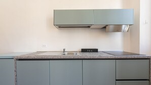 A kitchen with a sink, a countertop, cabinets, and a stove hood. - Santa Croce View 1 by Mmega (Firenze)