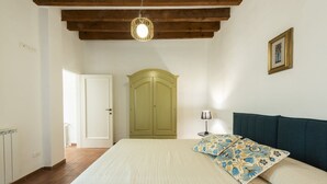 A bedroom with a bed, a wardrobe, a lamp, and a ceiling light. - Santa Croce View 2 apartment by Mmega (Firenze)
