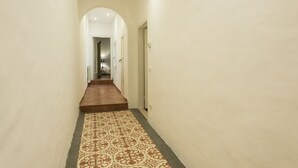 A narrow hallway with a patterned carpet, a wooden floor, and a door at the end. - Santa Croce View 2 apartment by Mmega (Firenze)