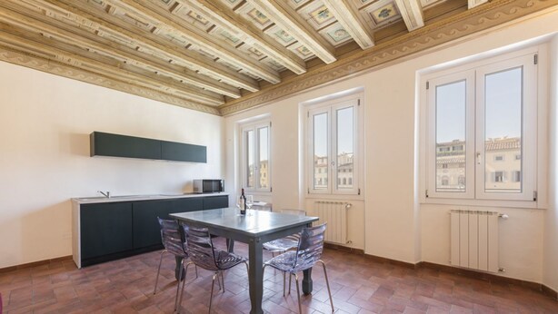 A kitchen with a dining table and chairs, a built-in oven, and a window with a view of buildings. - Santa Croce View 2 apartment by Mmega (Firenze)