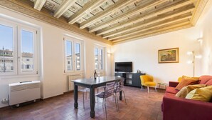 A living room with a dining table, chairs, a sofa, a TV, and a painting on the wall. - Santa Croce View 2 apartment by Mmega (Firenze)