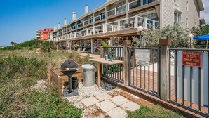 Un edificio de varios pisos con balcones, una zona de barbacoa y la entrada a la piscina con un cartel que indica que no hay socorrista de servicio.