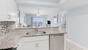 A modern kitchen with granite countertops, stainless steel appliances, and a view to the outside.