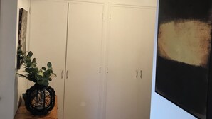 A hallway with a wooden cabinet, a potted plant, and a painting on the wall. - Adorable T2 apartment (45m2) in a residence with panoramic sea view (Jard-sur-Mer)