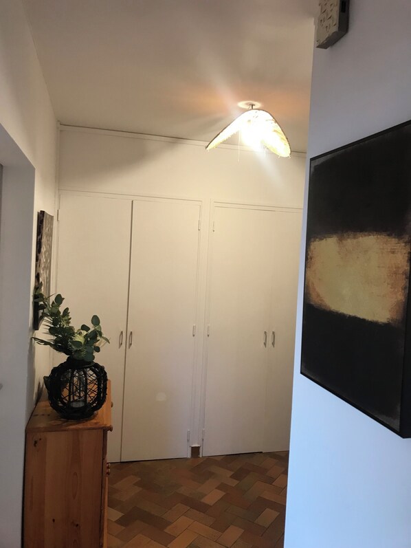 En hall med ett träskåp, en krukväxt och en tavla på väggen.
