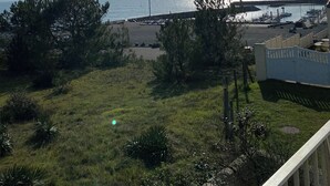 A coastal view with a grassy area, trees, and a marina with boats. - Adorable T2 apartment (45m2) in a residence with panoramic sea view (Jard-sur-Mer)