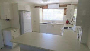 A kitchen with white cabinets, a refrigerator, a dishwasher, a stove, and a window with blinds.