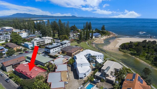 An aerial view of a coastal residential area with buildings, a beach, and a body of water.