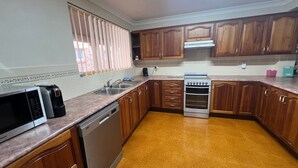 A kitchen with wooden cabinets, a built-in oven, a dishwasher, and a window with blinds. - Comfortable Townhouse with WIFI right in the heart of town. (South West Rocks)