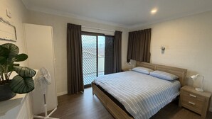 A bedroom with a bed, bedside table, lamp, and a potted plant. - CAMEO COURT UNIT 9 - Beautiful Unit close to town centre. (South West Rocks)