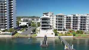 A modern hotel with multiple floors, a central courtyard, and a marina with a dock. - Sitka Penthouse Apartment (Maroochydore)