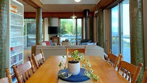 A dining area with a wooden table, chairs, and a potted plant. - Surf Shack - Beach Front (Separation Creek)
