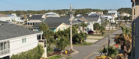 A residential street with houses, a stop sign, and a blue trash bin.
