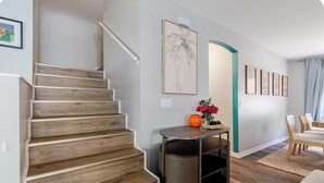 A staircase with wooden steps, a small table with a vase and a spherical object, and a dining area with chairs and a table. - Family Paradise: 5BR Kissimmee Home with Private Pool and Pet Friendly (Kissimmee)