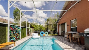 A swimming pool with a covered patio area, outdoor seating, and a grill. - Family Paradise: 5BR Kissimmee Home with Private Pool and Pet Friendly (Kissimmee)