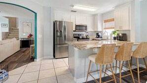 A modern kitchen with stainless steel appliances, a central island with bar stools, and a dining area. - Family Paradise: 5BR Kissimmee Home with Private Pool and Pet Friendly (Kissimmee)