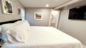 Een slaapkamer met een groot bed, een televisie en beelden in lijsten aan de muur.