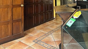 A hotel lobby with a large wooden door, a reception desk, and a fire extinguisher mounted on the wall. - Don Valentino (Antigua Guatemala)