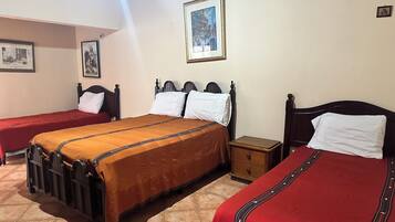 Een hotelkamer met twee enkele bedden, een houten nachtkastje, een klein houten dressoir en een ingelijst schilderij aan de muur.