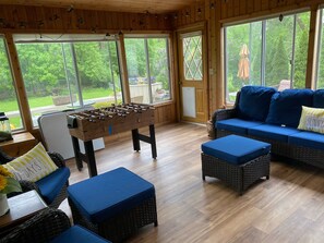 Relax in a serene space with a foosball table, comfortable seating, and a lush garden view.