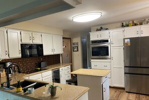 Enjoy cooking in this well-equipped kitchen with a refrigerator, oven, and microwave, along with ample storage space.