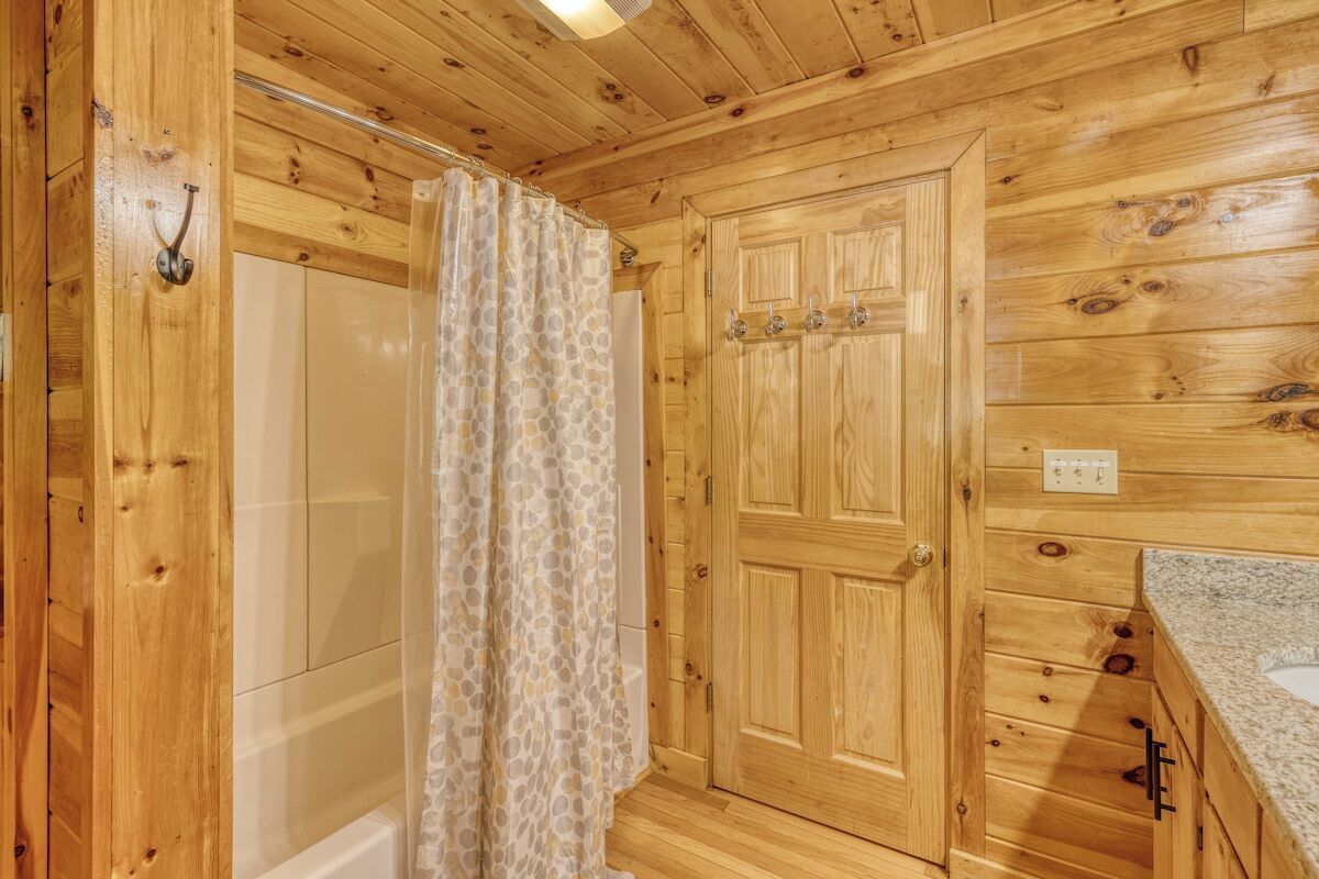 A wooden cabin bathroom with a shower, a toilet, and a sink.