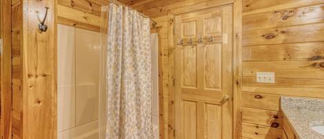 A wooden cabin bathroom with a shower, a toilet, and a sink.