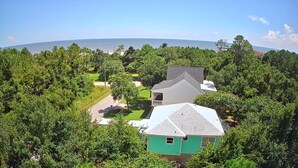 Zona residenziale con una casa circondata da vegetazione rigogliosa e una vista aperta sull'oceano.