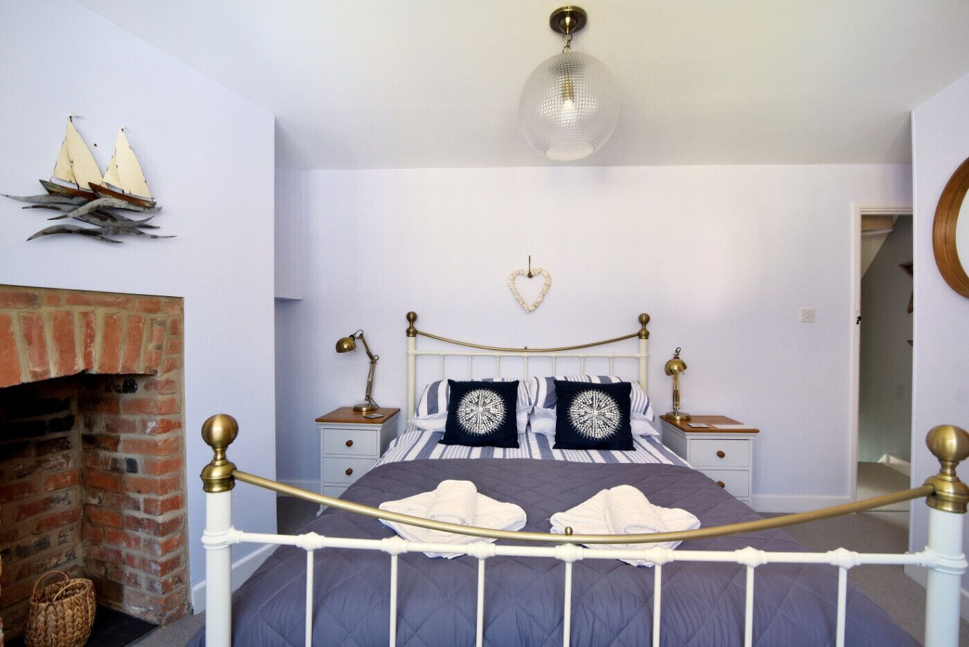 Een slaapkamer met een bed, nachtkastjes, een hanglamp, een hartvormige decoratie en een haard van baksteen.