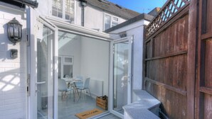 Een modern huis met een glazen deur die leidt naar een eetruimte met een tafel en stoelen.