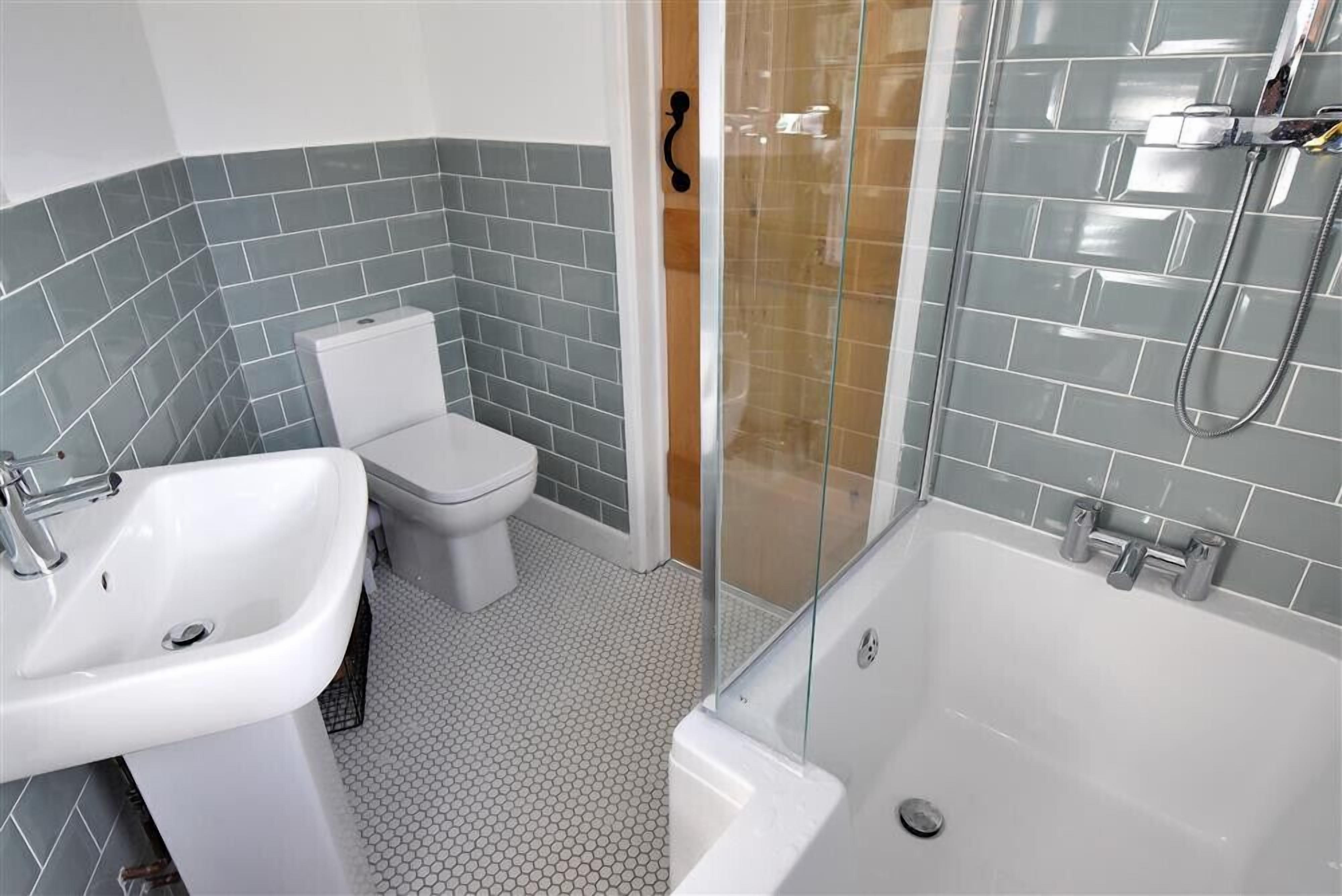 A bathroom with a white sink, toilet, and glass-enclosed shower area.