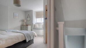 Een slaapkamer met een bed, nachtkastje, lamp en een raam met een radiator.