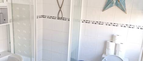Ein Badezimmer mit Duschkabine, Waschbecken in Weiß, Toilette in Blau und einer Stern-Dekoration an der Wand.