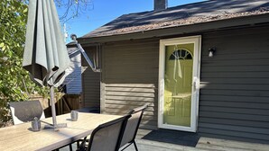 Un patio con una mesa, sillas, una puerta y una ventana.