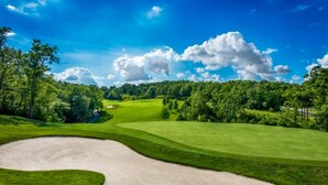 Un parcours de golf doté d’un bunker de sable, d’une pelouse bien entretenue et d’un ciel bleu dégagé.